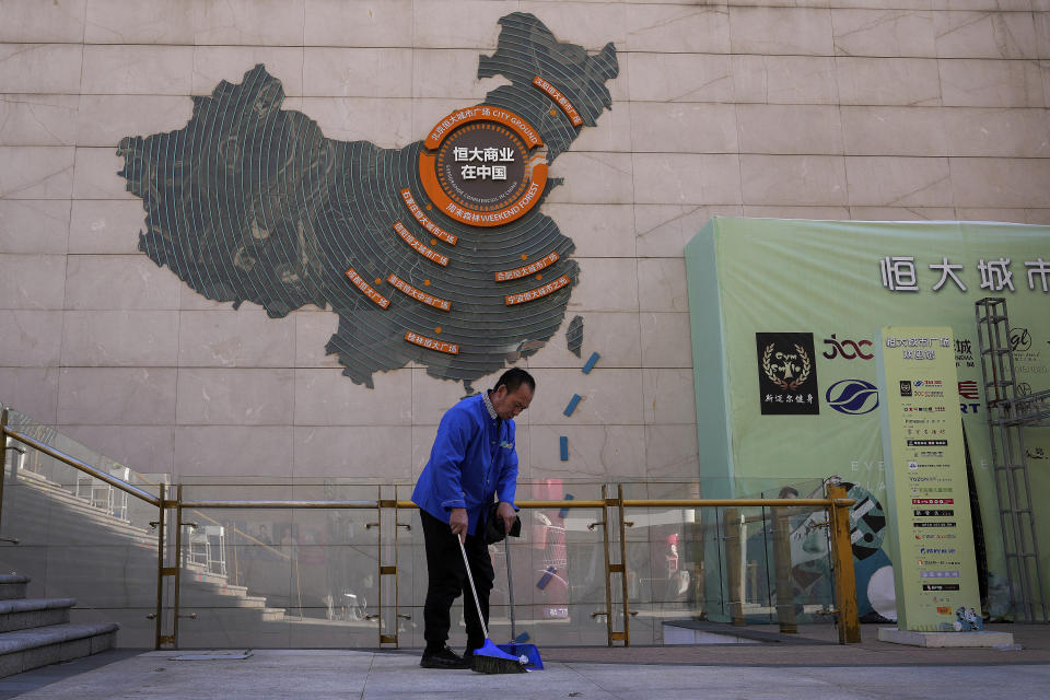 A cleaner sweeps near a map showing Evergrande development projects in China on a wall in an Evergrande city plaza in Beijing on Sept. 21, 2021. China’s central bank expanded the supply of money for lending Monday, Dec. 6, 2021, as Beijing tried to reassure its public and investors the economy can be protected if a troubled real estate developer’s $310 billion mountain of debt collapses. (AP Photo/Andy Wong)