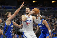 Los Angeles Clippers center Ivica Zubac (40) takes a shot against Orlando Magic forward Franz Wagner (22) and forward Paolo Banchero (5) during the second half of an NBA basketball game, Friday, March 29, 2024, in Orlando, Fla. (AP Photo/John Raoux)