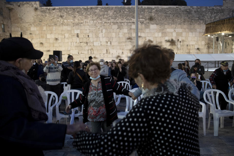 Holocaust survivors dance during a Hanukkah menorah lighting ceremony in their honor at the Western Wall, in the Old City of Jerusalem, Tuesday, Nov. 30, 2021. Holocaust survivors marked the third night of Hanukkah on Tuesday with a menorah-lighting ceremony at Jerusalem's Western Wall that paid tribute to them and the 6 million other Jews who were killed by the Nazis. (AP Photo/Maya Alleruzzo)