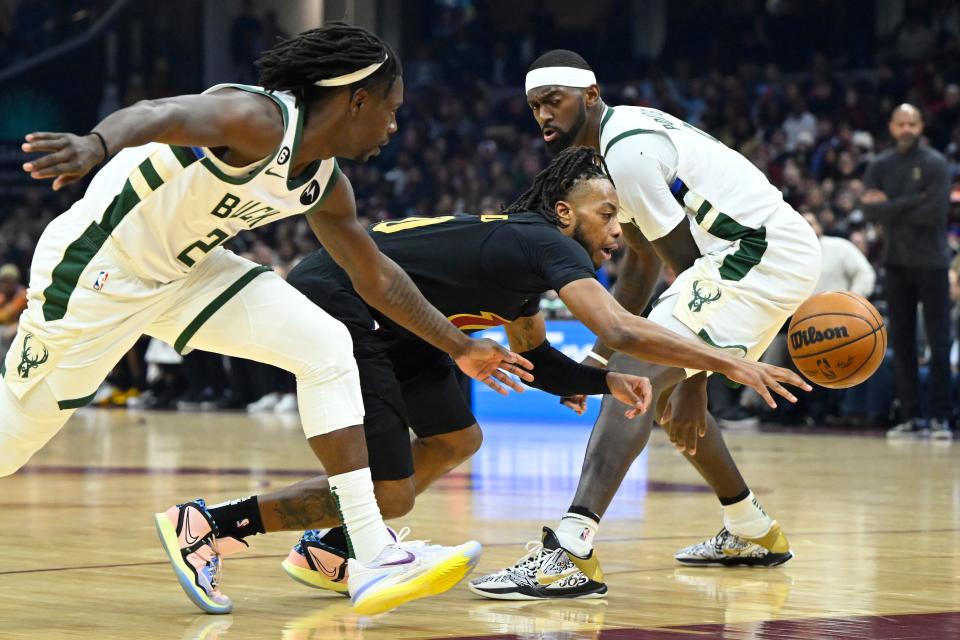 Cavaliers guard Darius Garland loses control of the ball as he attempts to drive between Bucks guard Jrue Holiday and forward Bobby Portis during the second quarter Saturday night.