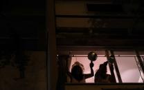 Women bang pots at the window of their house as they protest against Brazilian President Jair Bolsonaro during the coronavirus disease (COVID-19) outbreak in Rio de Janeiro