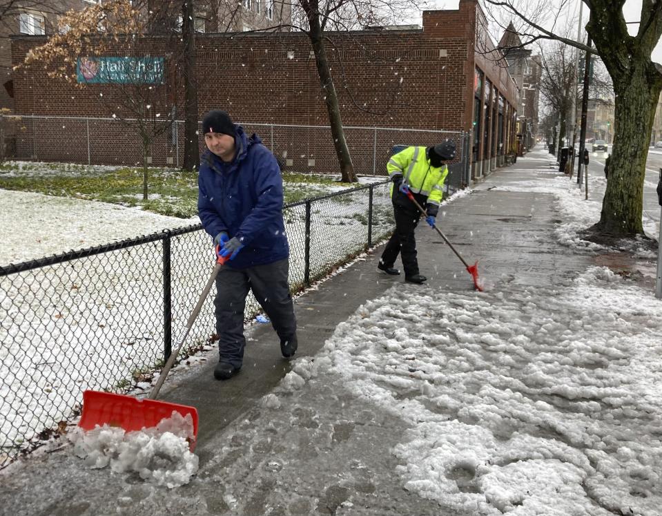Two workers clear snow and slush from sidewalks Sunday, Jan. 7, 2024 in Cambridge, Mass. as a storm bringing a wintry mix of precipitation bears down on the New England region. (AP Photo/Steve LeBlanc)