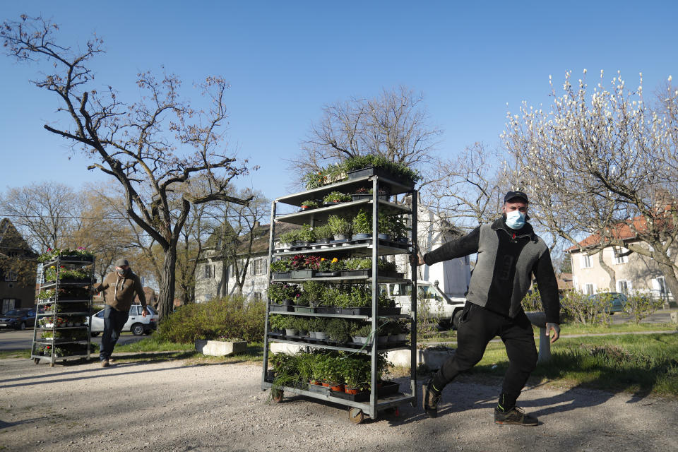 Staff members of a flower shop drag merchandise carts in Budapest, Hungary, Wednesday April 7, 2021. Hungary's government lifted several lockdown restrictions on Wednesday, even as some doctors and medical experts urged caution after a record-breaking day of COVID-19 deaths, a move that came as Hungary reached 2.5 million first-dose vaccinations, a benchmark the government set for when a gradual reopening could move forward. (AP Photo/Laszlo Balogh)