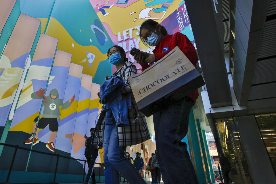 Shoppers wearing face masks to help curb the spread of the coronavirus with their purchased goods walk through the capital city's popular shopping mall in Beijing, Monday, Oct. 19, 2020. China’s shaky economic recovery from the coronavirus pandemic is gaining strength as consumers return to shopping malls and auto dealerships while the United States and Europe endure painful contractions. (AP Photo/Andy Wong)