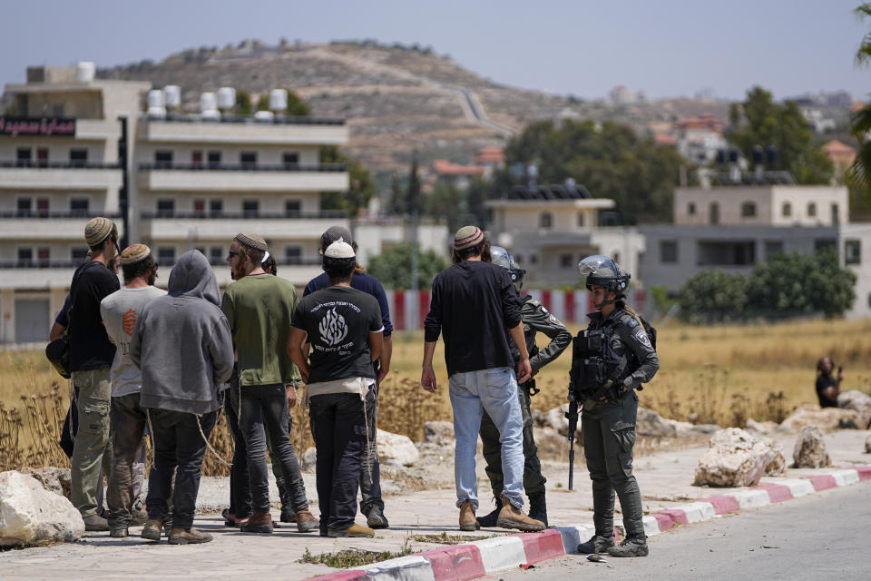 Israeli border police officers stop Jewish settlers from entering the Palestinian West Bank town of Turmus Ayya, Wednesday, June 21, 2023. Israeli settlers set fire to Palestinian cars after four Israelis were killed by Palestinian gunmen in the northern West Bank on Tuesday. (AP Photo/Ohad Zwigenberg)