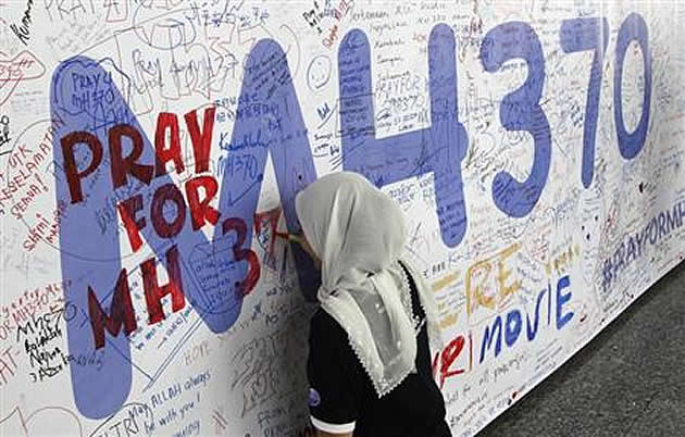 A woman writes on a banner of well wishes for the passengers of the missing Malaysia Airlines Flight MH370 at Kuala Lumpur International Airport March 14, 2014. (REUTERS/Edgar Su)