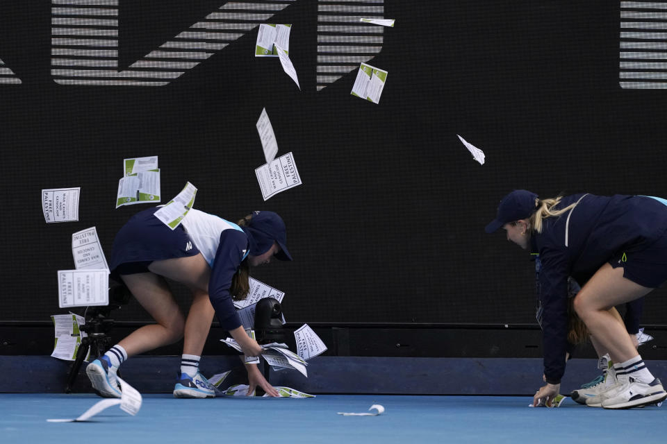 Ball kids pickup "free Palestine" leaflets thrown onto Margaret Court Arena during the fourth round match between Alexander Zverev of Germany and Cameron Norrie of Britain at the Australian Open tennis championships at Melbourne Park, Melbourne, Australia, Monday, Jan. 22, 2024. (AP Photo/Alessandra Tarantino)