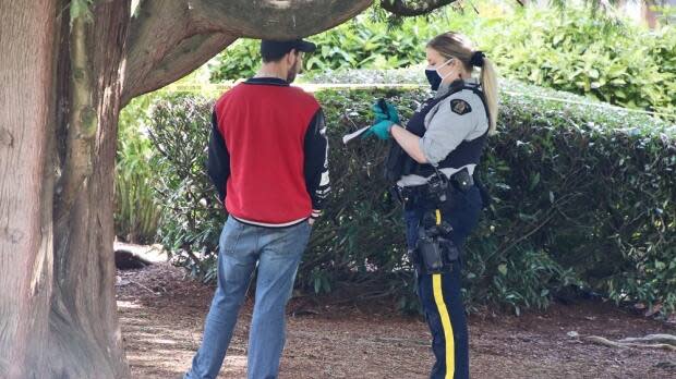 An RCMP officer speaks to a man at the scene of a shooting in Coquitlam on Sunday April 4, 2021.