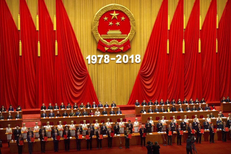 Attendees are presented with medallions during a conference to commemorate the 40th anniversary of China's Reform and Opening Up policy at the Great Hall of the People in Beijing, Tuesday, Dec. 18, 2018. (AP Photo/Mark Schiefelbein)