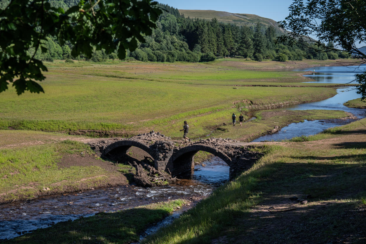 MERTHYR TYDFIL, WALES - AUGUST 11: A man walks over an exposed bridge that is normally submerged at Llwyn Onn Reservoir amid the ongoing heat wave on August 11, 2022 near Merthyr Tydfil, Wales. The UK's Met Office has issued an amber heat warning for the next four days with temperatures expected to hit 37C in some parts of the country. (Photo by Carl Court/Getty Images)