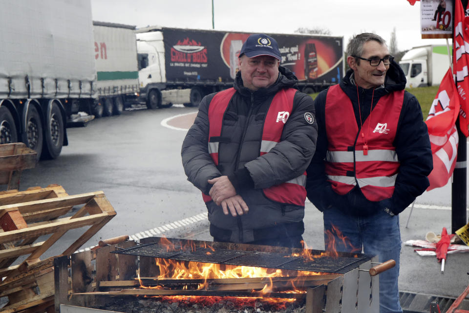 Members of truck trade unions block the access to a transportation center in Lille, northern France, Tuesday, March 7, 2023. Garbage collectors, utility workers and train drivers are among people walking off the job Tuesday across France. They are expressing anger at a bill raising the retirement age to 64, which unions see as a broader threat to the French social model. (AP Photo/Michel Spingler)