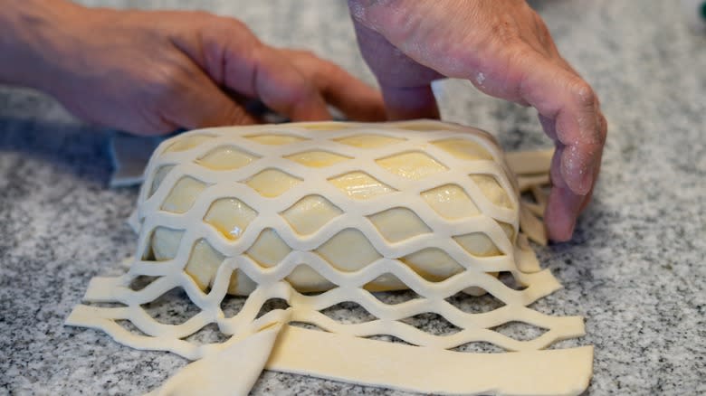 Person wrapping beef Wellington in pastry