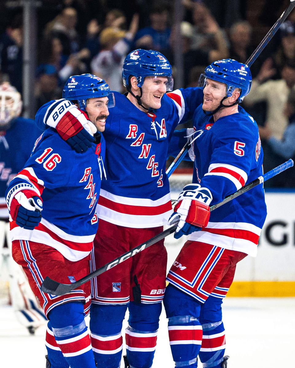 New York Rangers' Vincent Trocheck (16) and Chad Ruhwedel (5) celebrate with Adam Fox after Fox scored against the Philadelphia Flyers in overtime of an NHL hockey game Tuesday, March 26, 2024 in New York. (AP Photo/Peter K. Afriyie)