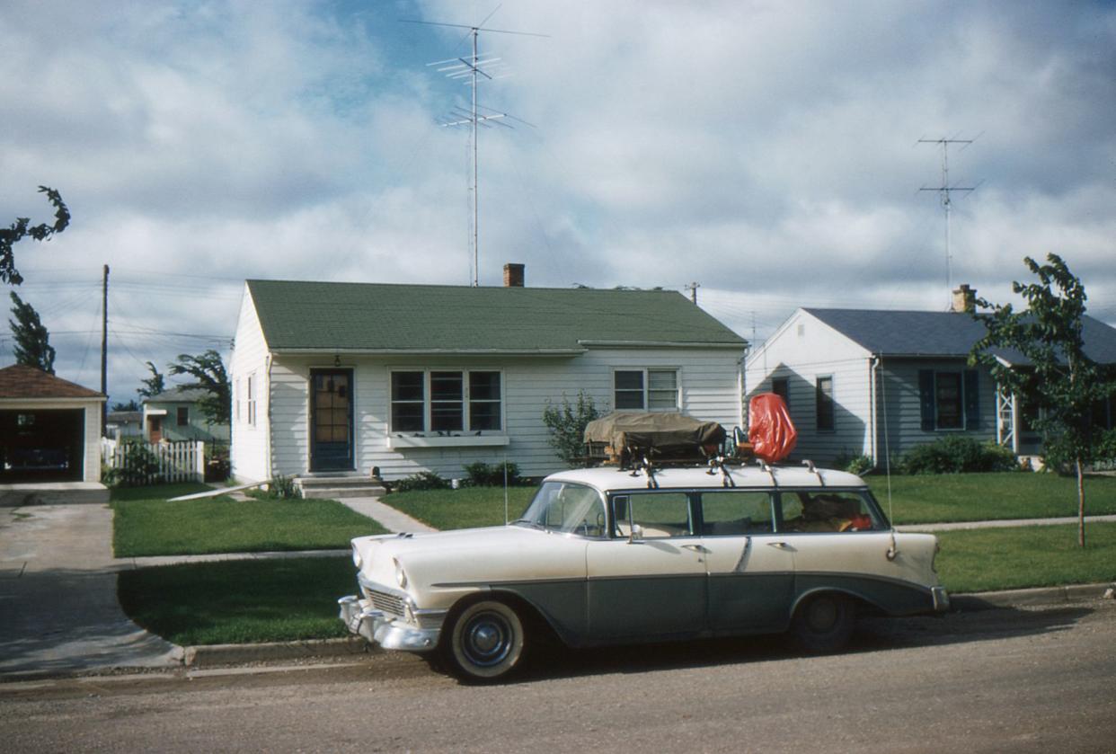 1956 Chevrolet station wagon packed for vacation in front of new tract house with TV antenna. Symbols of the affluent post WWII society in USA. Waterloo, Iowa, 1957. Kodachrome scanned film with grain