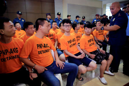 Philippine National Police (PNP) Chief Ronald Dela Rosa (R) confronts some of the 43 arrested foreigners, mostly Chinese nationals, for kidnapping a Singaporean woman at a casino resort in the capital, during a presentation inside the PNP Headquarters in Quezon City, Metro Manila, Philippines July 20, 2017. REUTERS/Romeo Ranoco