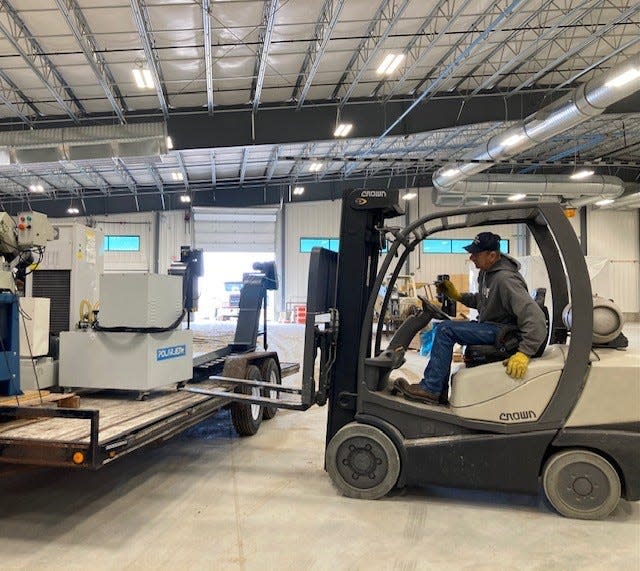 An employee uses a forklift to unload a machine being moved to the new machine floor.  The multi million dollar expansion is expected to streamline production and save time and resources.