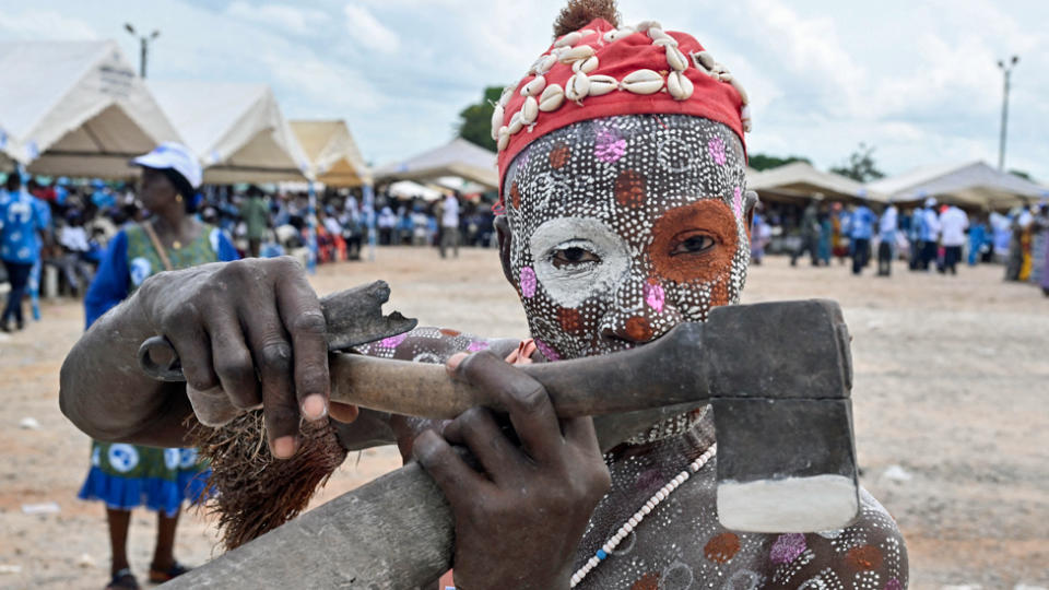 A supporter of Ivory Coast's ex-President Laurant Gbagbo with body paint decorations and an axe in Agboville, Ivory Coast - Saturday 6 April 2024