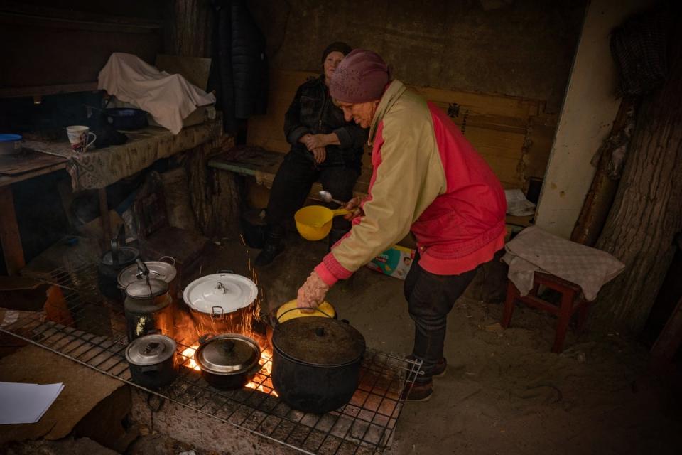 Olha kocht Essen, das ihr von Wohltätigkeitsorganisationen gegeben wurde, beim Grillen in einer provisorischen Hütte, die ihr Nachbar gebaut hat (Bel Trew)