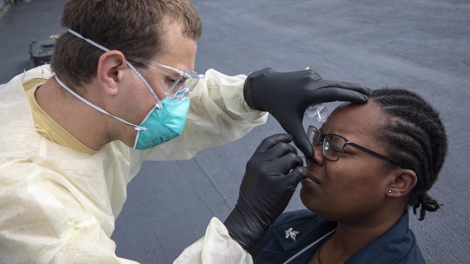 Hospital Corpsman 1st Class Jonmichael Heldorfer, left, performs a COVID-19 test on Cryptologic Technician (Technical) 2nd Class Nareba Brady aboard a ship while in Gaeta, Italy, on May 6, 2020. (MC1 Kyle Steckler/U.S. Navy)