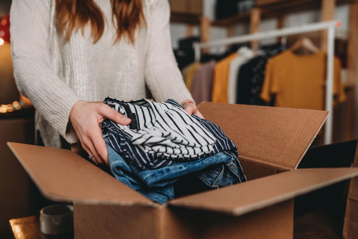 A millennial woman is preparing the shipment of some clothes in her new online shop. She's the owner of an online thrift store. New small business concept.