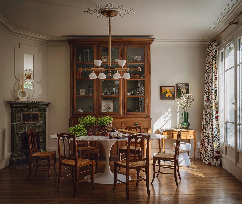 The dining room is furnished with a Saarinen table, vintage French chairs, an antique cabinet from Selency, and a custom mirror.