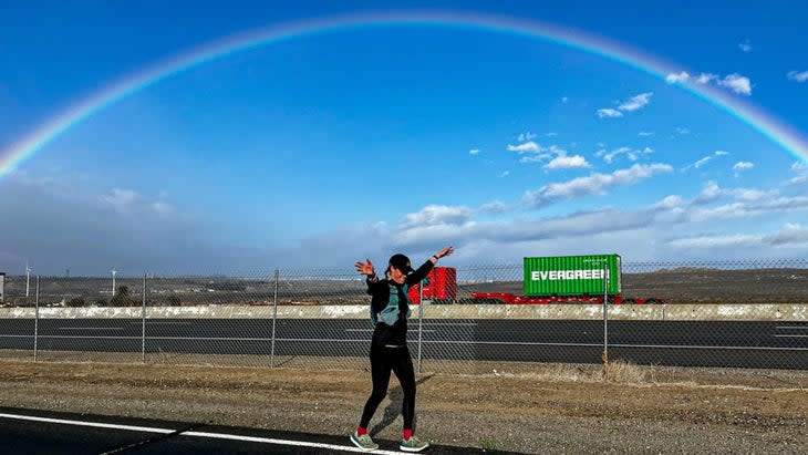 Lucy runs on a road under a rainbow