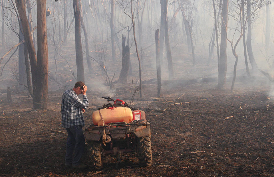 A farmer rubs his eyes as as a fire burns through his Victorian property. Source: Getty