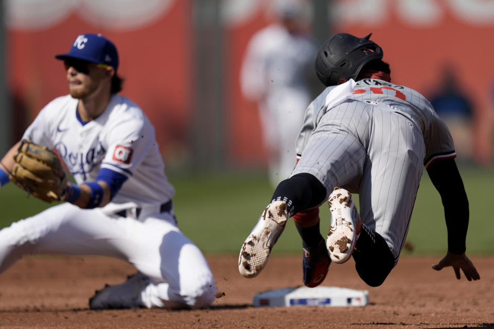 Minnesota Twins' Willi Castro, right, dives to second before being caught stealing by Kansas City Royals shortstop Bobby Witt Jr. during the third inning of a baseball game Saturday, March 30, 2024, in Kansas City, Mo. (AP Photo/Charlie Riedel)