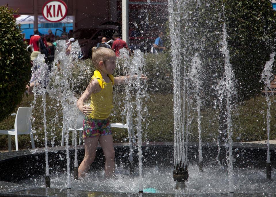 A young spectator cools herself down in in the fountain in Garden Square as play was suspended when organizers implemented the Extreme Heat policy during second round matches at the Australian Open tennis championship in Melbourne, Australia, Thursday, Jan. 16, 2014.(AP Photo/Joshua Baker)