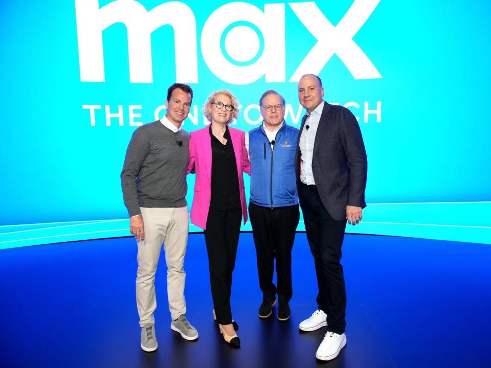 Warner Bros. Discovery execs Casey Bloys, Kathleen Finch, David Zaslav, and JB Perrette on stage in front of a blue screen with the Max logo in white
