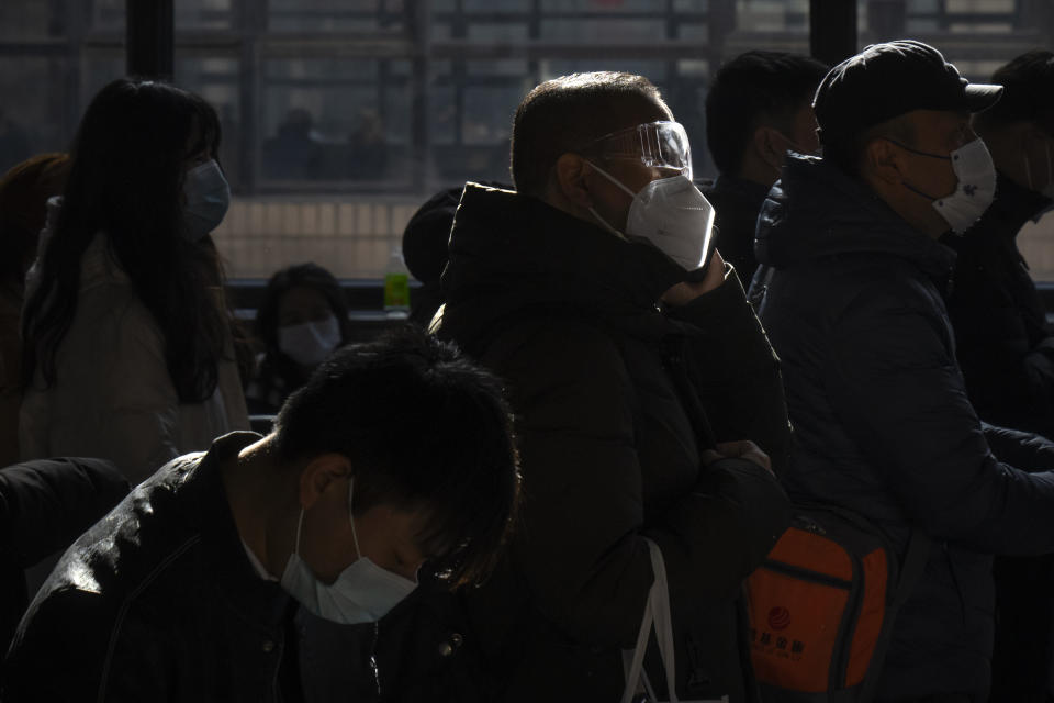 A traveler wearing goggles and a face mask stands in line to board a train at Beijing West Railway Station in Beijing, Wednesday, Jan. 18, 2023. China in December lifted its strict "zero-COVID" policy, letting loose a wave of pent-up travel desire, particularly around China's most important time for family gatherings, referred to in China as the Spring Festival, that may be the only time in the year when urban workers return to their hometowns. (AP Photo/Mark Schiefelbein)