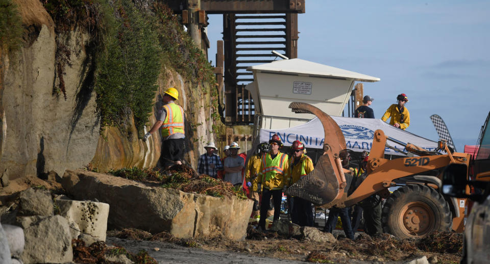 Teams work at Grandview Beach in California after three people were killed by a falling cliff.