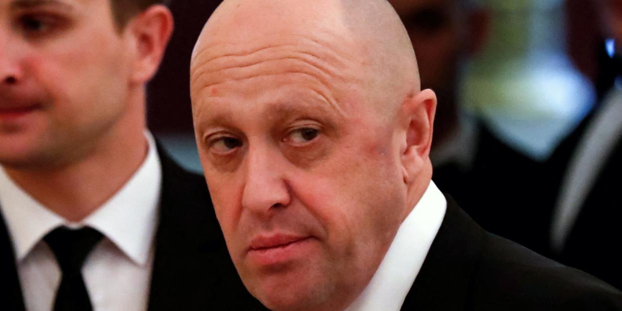 Yevgeny Prigozhin sitting at a table with other people while wearing a black suit and a silver tie at a formal event.
