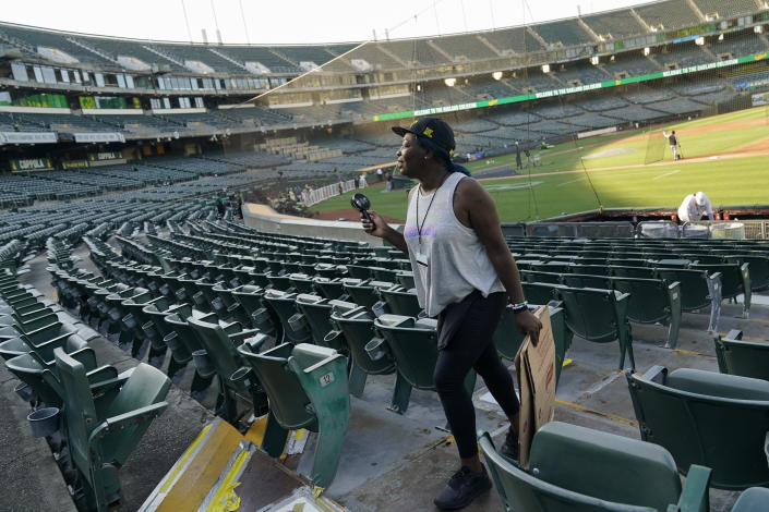 FILE - Tina Walker, who works as a server at RingCentral Coliseum, uses a portable fan to cool off before a baseball game between the Oakland Athletics and the Chicago White Sox in Oakland, Calif., Thursday, Sept. 8, 2022. The record-breaking heat that has pushed the state's electrical grid to the brink of power outages for more than a week is almost over but it is a sign of things to come. (AP Photo/Godofredo A. Vásquez, File)