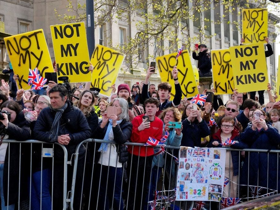 Protesters hold signs reading "Not My King" ahead of King Charles' arrival at an event