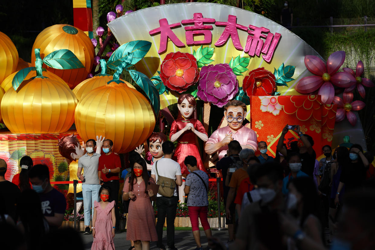 People in protective mask take photo with a lantern display during the River Hongbao festival, held as part of the Chinese New Year celebration at Gardens by the Bay on February 3, 2022 in Singapore. (Photo by Suhaimi Abdullah/NurPhoto via Getty Images)