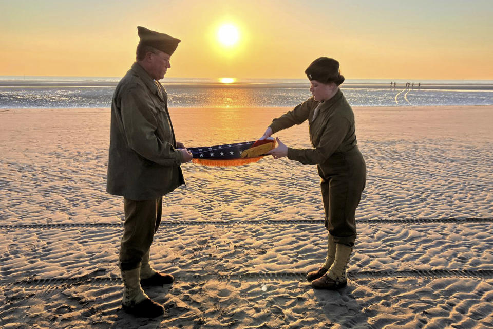 Christophe Receveur y su hija Julie, de Francia, extienden una bandera estadounidense que él compró hace seis meses en Gettysburg, Pensilvania, para conmemorar el Día D, el jueves 6 de junio de 2024 en la playa Utah, Normandía. (AP Foto/John Leicester)