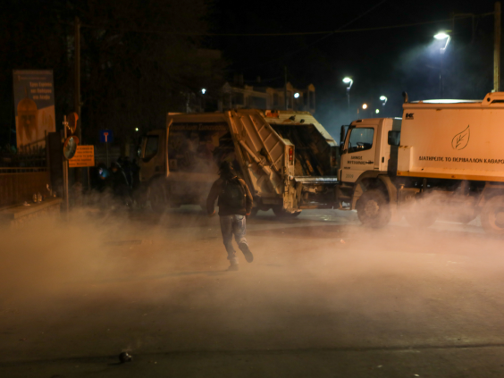 Tear gas swirls around bin lorries commandeered by protesters to block the roads (Reuters)