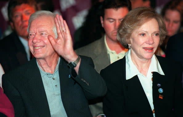 Former US President Jimmy Carter (L) waves to the crowd as he sits with his wife, Roslyn (R),  at the 1998 Goodwill Games boxing finals 01 August at Madison Square Garden in New York (AFP via Getty Images)
