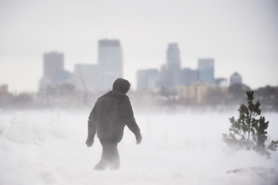 A man goes for a walk in front of the Minneapolis skyline during a snowstorm on February 22, 2023. For the first time in nearly two years, a significant snowstorm could hit the Mid-Atlantic this weekend.