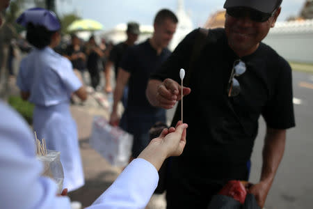 A mourner receives ammonia-soaked cotton wool handed out by medical rescue teams to help prevent fainting as he waits to pay his respects to Thailand's late King Bhumibol Adulyadej at the Grand Palace in Bangkok, Thailand, October 15, 2016. REUTERS/Athit Perawongmetha