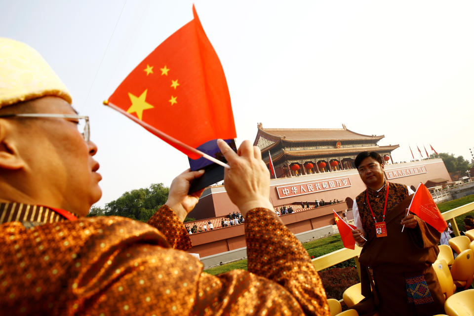 A Yunnan delegate holding Chinese flags poses for pictures with Tiananmen Gate in the background before a military parade marking the 70th founding anniversary of People's Republic of China, on its National Day in Beijing, China October 1, 2019.  (Photo: Thomas Peter/Reuters)