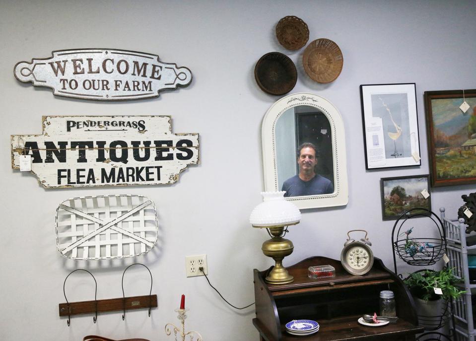 Keith Lemerise, owner of Water Street Marketplace, is reflected in a mirror on the wall at his shop in downtown Exeter.