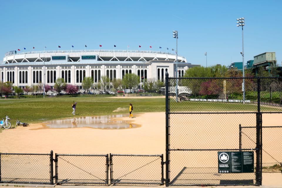 Youngsters play by a puddle where the former Yankee Stadium used to stand. Thursday, April 13, 2023 