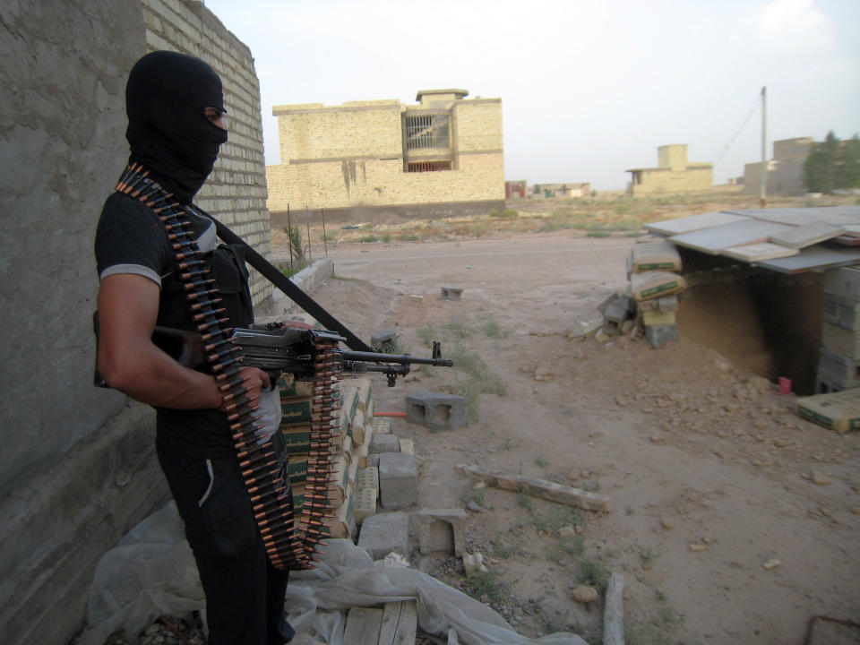 In this Monday, April 28, 2014 photo, a masked anti-government gunman holds his weapon as he stands guard in Fallujah, Iraq. Al-Qaida-linked fighters and their allies seized the city of Fallujah and parts of the Anbar provincial capital Ramadi in late December after authorities dismantled a protest camp. Like the camp in the northern Iraqi town of Hawija whose dismantlement in April sparked violent clashes and set off the current upsurge in killing, the Anbar camp was set up by Sunnis angry at what they consider second-class treatment by the Shiite-led government. (AP Photo)