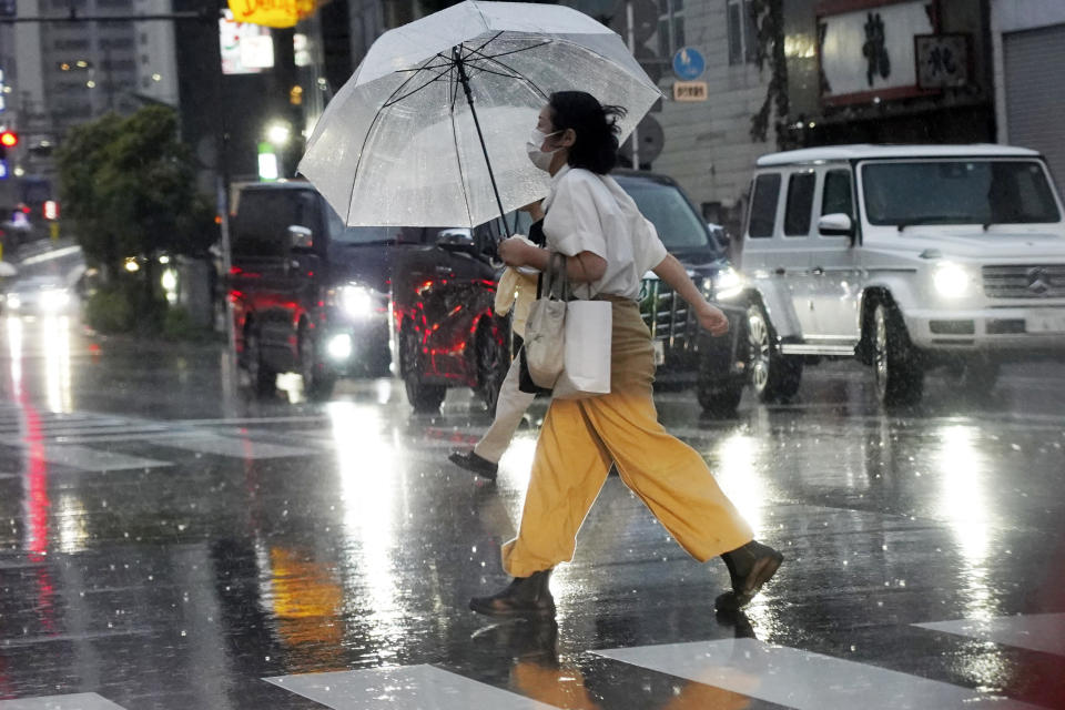 A person holds an umbrella against strong wind and rain as he walks on a street Friday, June 2, 2023, in Kawasaki near Tokyo, as a tropical storm was approaching. (AP Photo/Eugene Hoshiko)