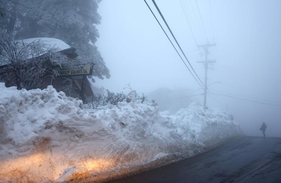 A person walks near a snow berm on 6th March after a series of winter storms dropped more than 100 inches of snow in the San Bernardino Mountains in Southern California (Getty Images)