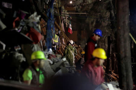 Rescue workers stand next to the rubble of a collapsed multi family residential after an earthquake in Mexico City, Mexico September 21, 2017. REUTERS/Daniel Becerril