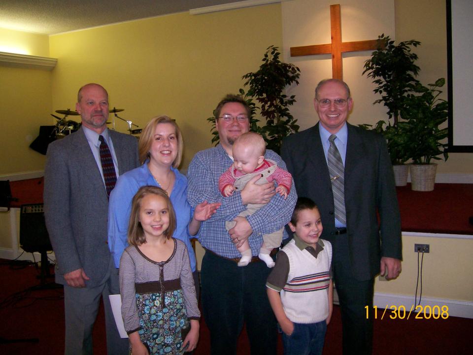 Megan and Dominique Benninger, center, stand with pastors Donald Foose, left, and Bob Conrad, right, at the dedication ceremony for their son, Alexander, in 2008.