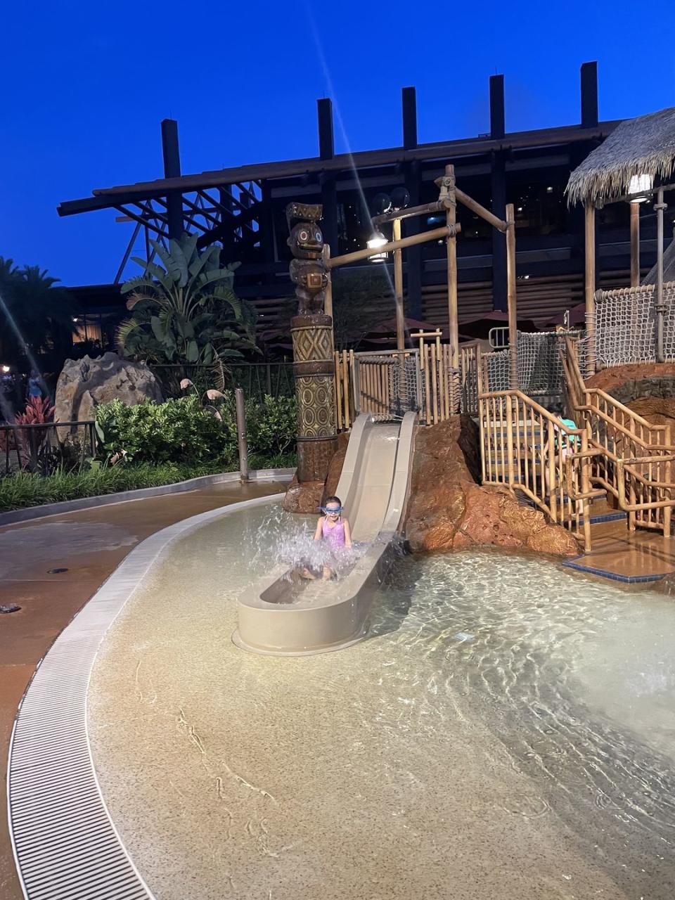 a child going down a water slide and disney polynesian village resort